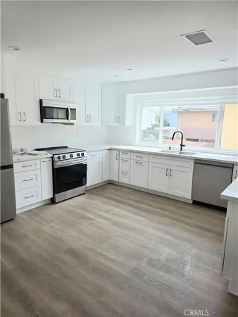 a large white kitchen with granite countertop a stove top oven a sink and dishwasher