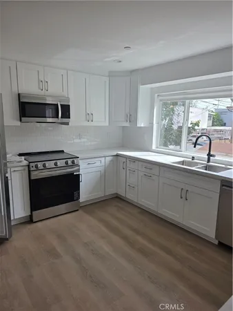 a kitchen with granite countertop white cabinets and stainless steel appliances