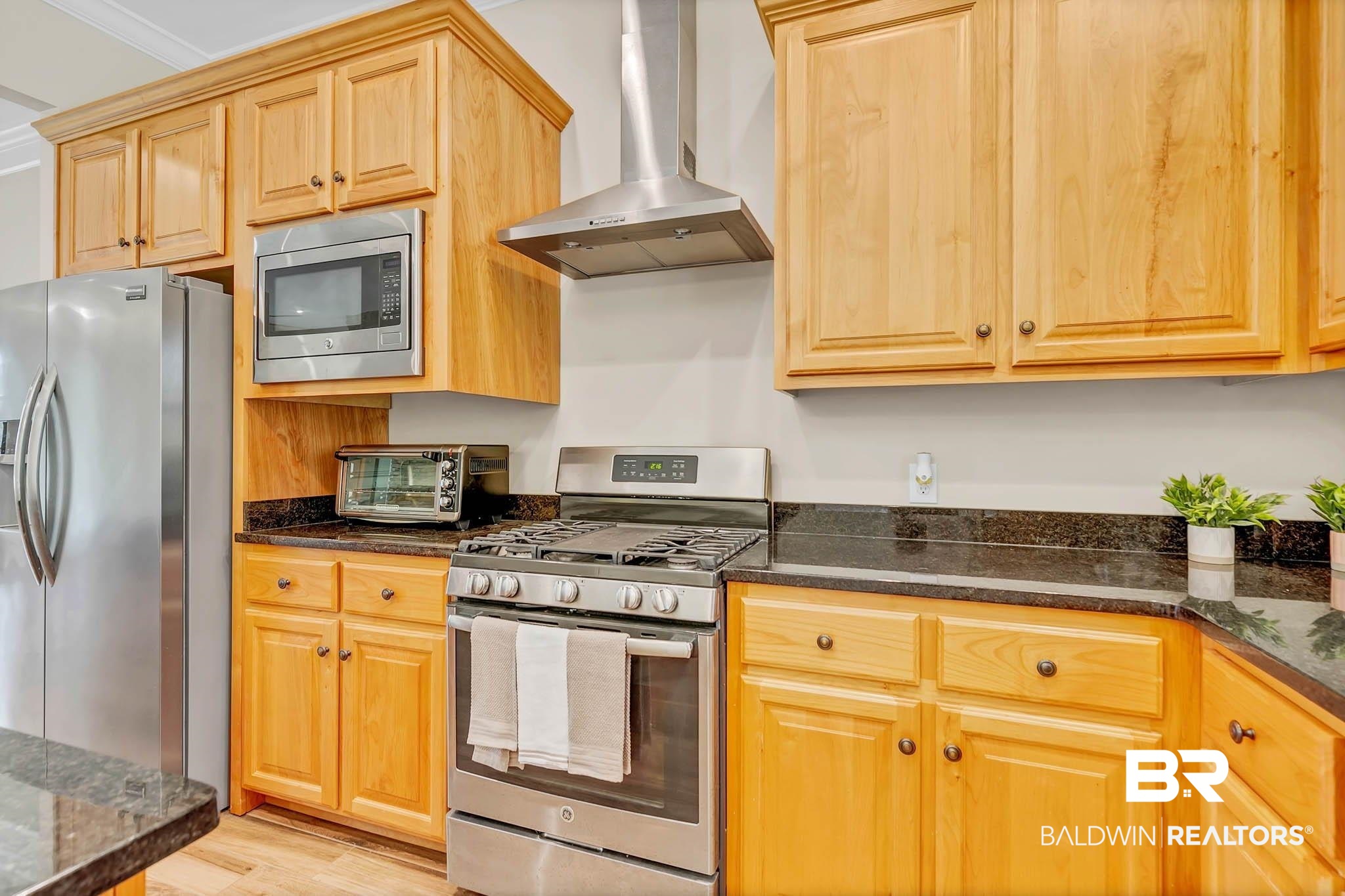 8145 Bay View Drive Foley, AL 36535 - Photo 22 of 81 Kitchen with stainless steel appliances, wall chimney range hood, light wood-style flooring, and dark stone counters