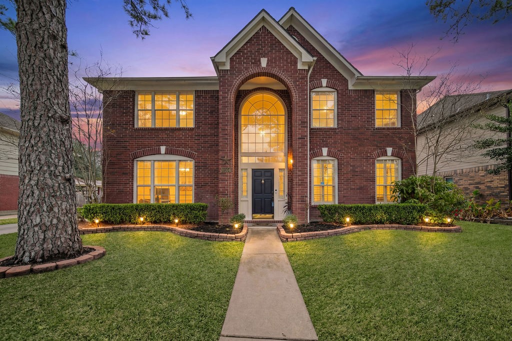 16114 Kintyre Point Road Houston, TX 77095 - Photo 1 of 44 A stunning two-story brick home with large windows and a welcoming front entrance. The beautifully landscaped yard features a paved walkway and accent lighting, enhancing its curb appeal against a picturesque sunset backdrop.