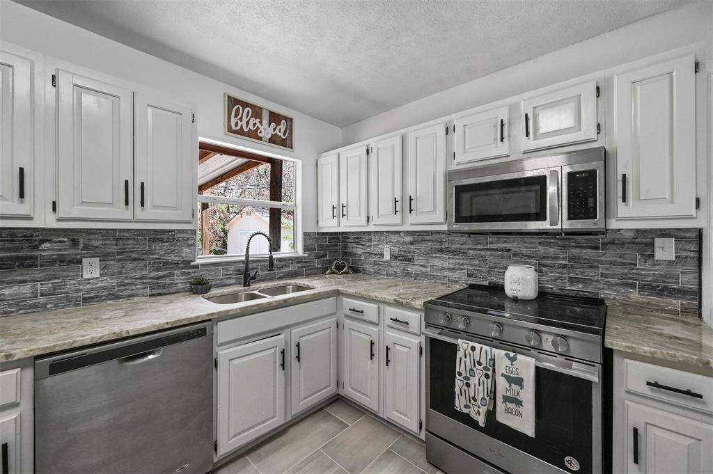 11817 Rupley Lane Dallas, TX 75218 - Photo 1 of 1 Kitchen with sink, light tile patterned flooring, a textured ceiling, white cabinets, and appliances with stainless steel finishes