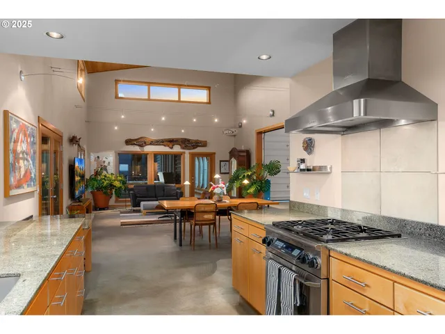 a kitchen with stainless steel appliances granite countertop a stove and a view of living room