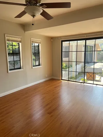 a view of an empty room with wooden floor and a window