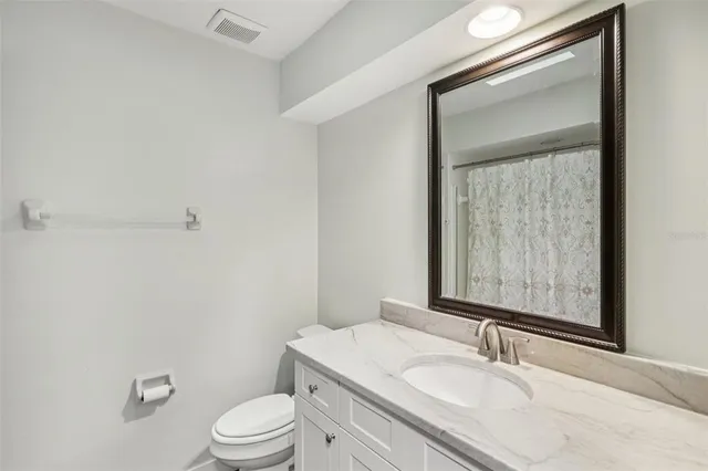 a bathroom with a granite countertop sink toilet a mirror and a tub
