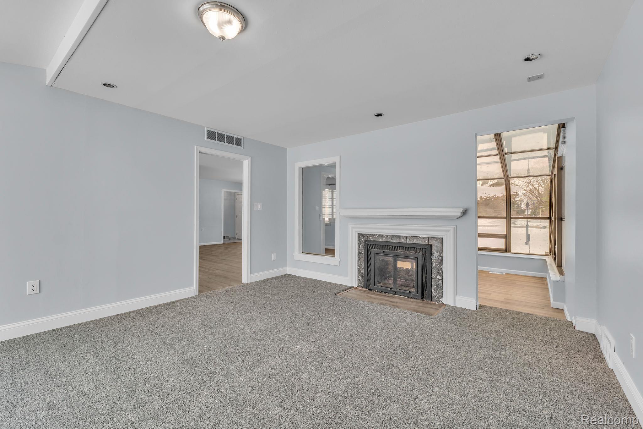 6576 Inkster Road West Bloomfield, MI 48322 - Photo 32 of 62 Unfurnished living room with carpet floors, a fireplace, and plenty of natural light