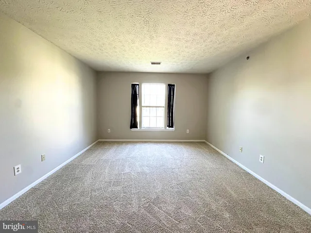a view of an empty room with window and closet area