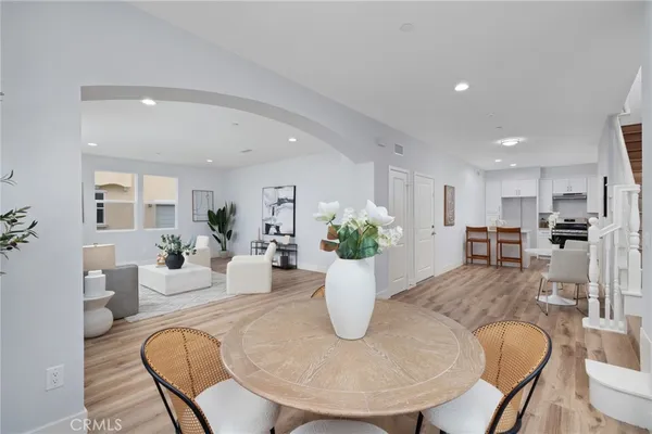 a dining room with furniture a potted plant and a kitchen view