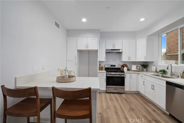 a kitchen with stainless steel appliances granite countertop a stove a sink dishwasher and a refrigerator with wooden cabinets