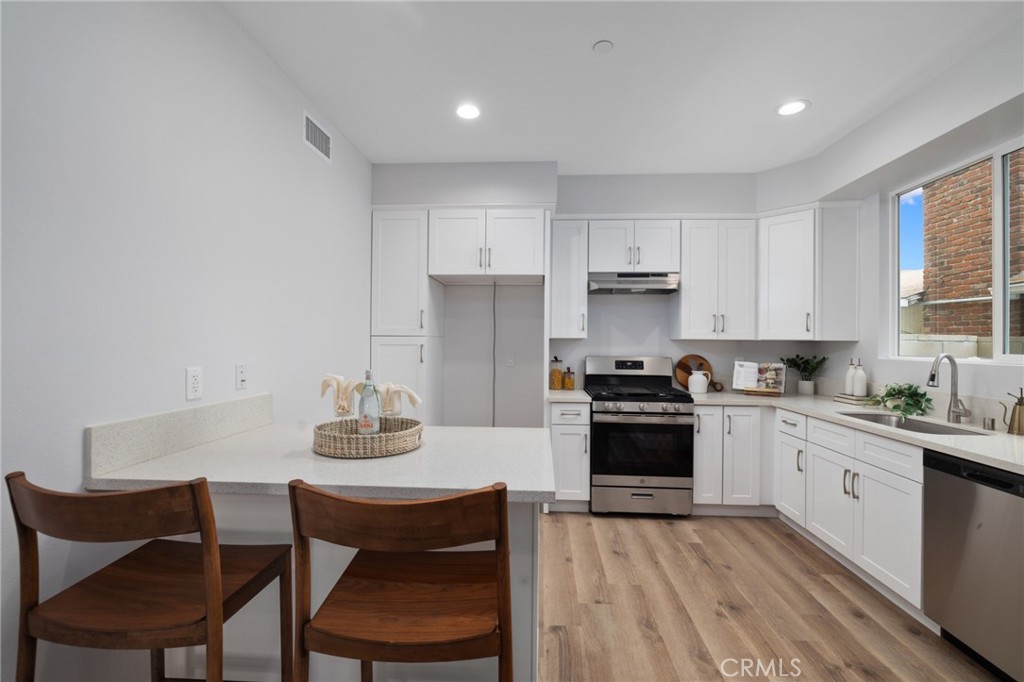 11237 Gladhill Road, Unit 4 Whittier, CA 90604 - Photo 13 of 34 a kitchen with stainless steel appliances granite countertop a stove a sink dishwasher and a refrigerator with wooden cabinets