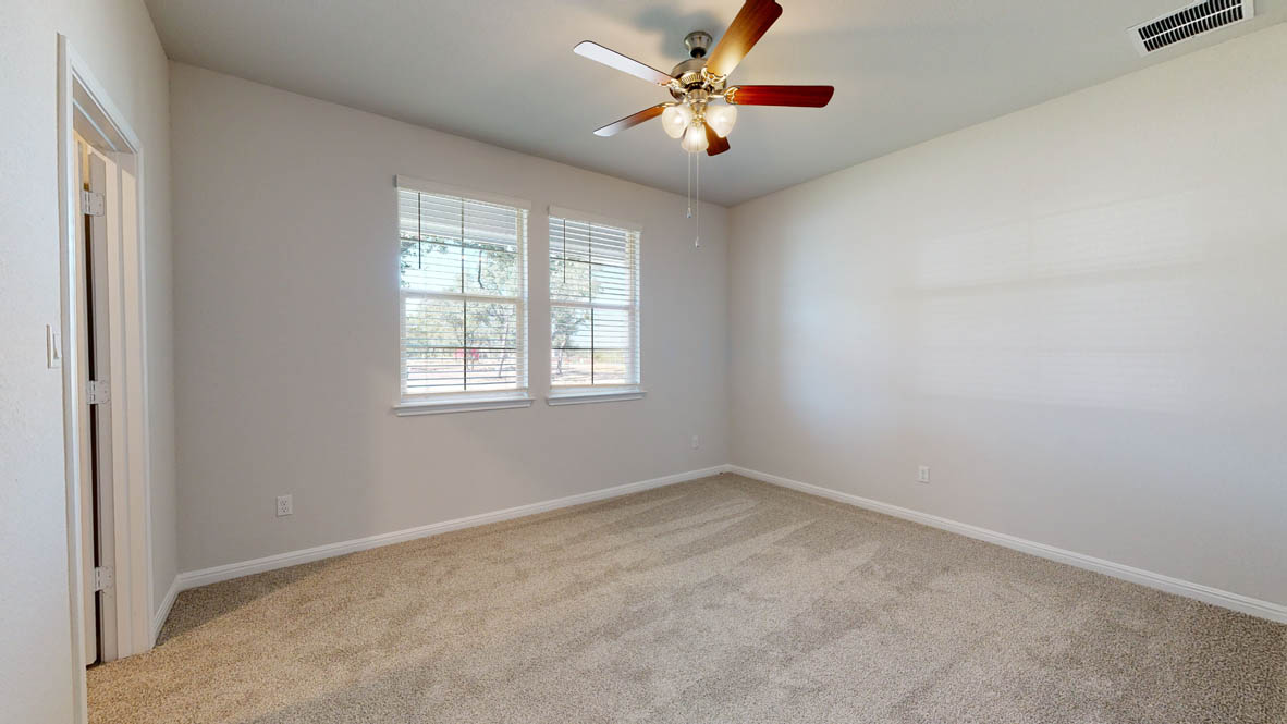 808 Gauge Road Thorndale, TX 76577 - Photo 17 of 31 A well-lit bedroom provides comfort and style, with twin windows and a ceiling fan.
