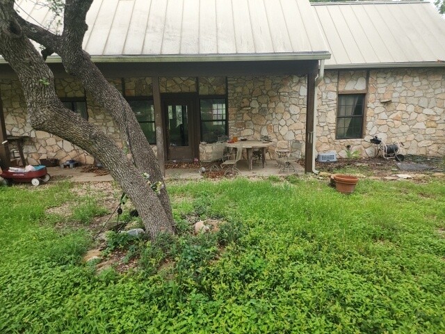 12011 Buckner Road Austin, TX 78726 - Photo 3 of 40 A quaint stone-faced home with a durable metal roof offers a shaded patio retreat.