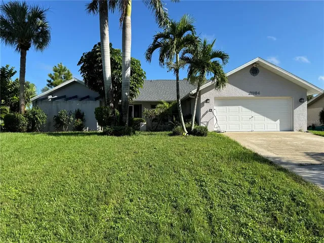 a view of a house with a yard and palm trees