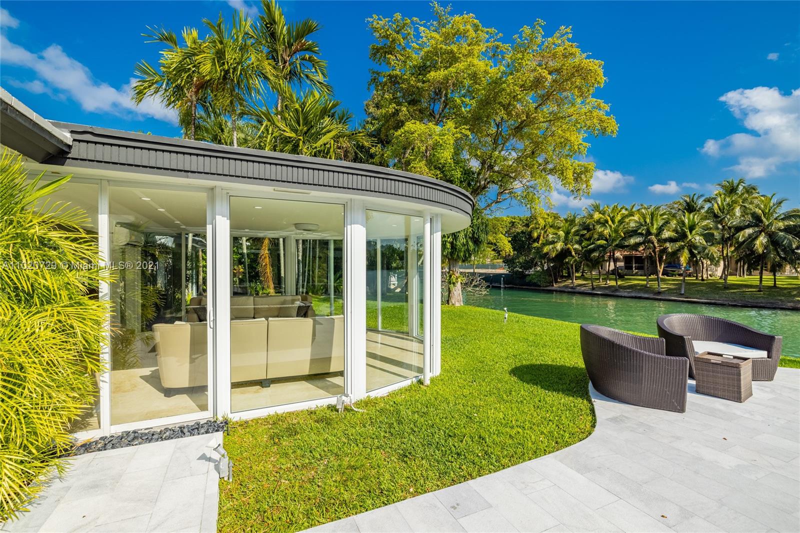 4765 Lake Road Miami, FL 33137 - Photo 57 of 100 a view of a patio with chairs potted plants and floor to ceiling window and wooden fence