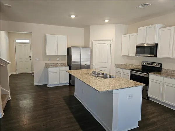 a kitchen with stainless steel appliances kitchen island a sink dishwasher a refrigerator and a stove with wooden floor