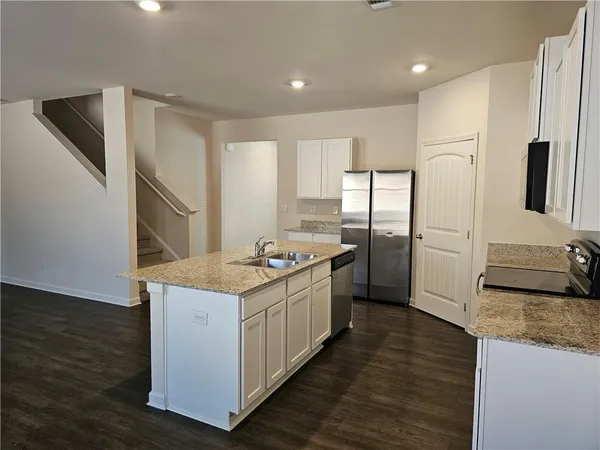 a kitchen with stainless steel appliances granite countertop a refrigerator a sink and a stove