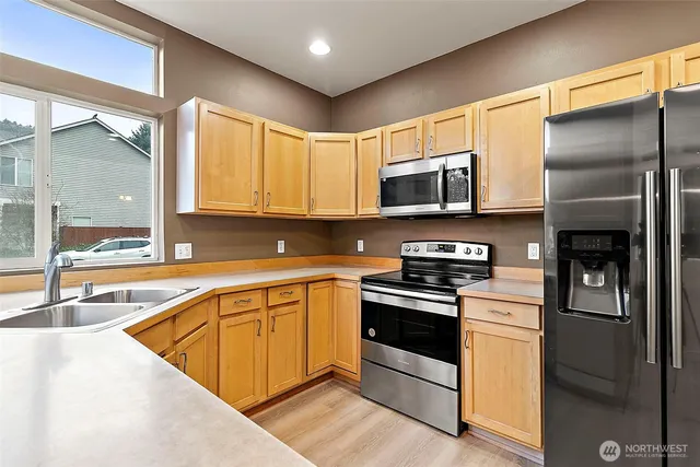 a kitchen with stainless steel appliances granite countertop a stove a sink and a microwave