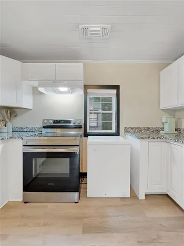a kitchen with granite countertop a stove top oven a sink and cabinets