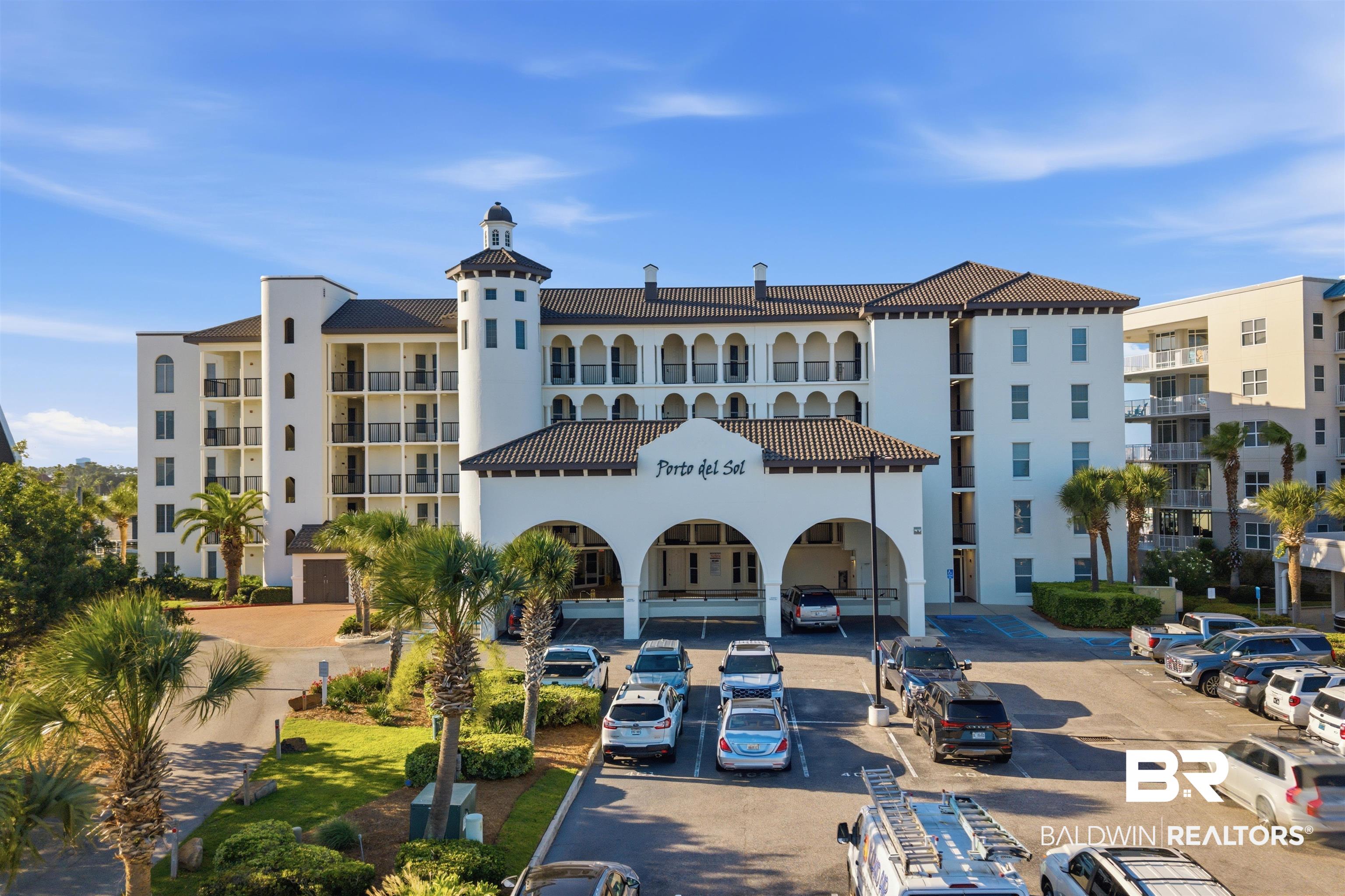 3564 Bayou Road, Unit 203 Orange Beach, AL 36561 - Photo 1 of 53 Stately condominium building featuring a stucco exterior, tiled roof, and a prominent arched porte-cochère entrance