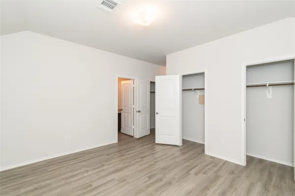 a view of an empty room with wooden floor and closet