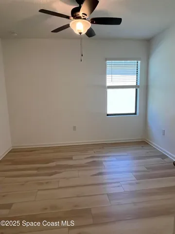 an empty room with wooden floor closet and windows