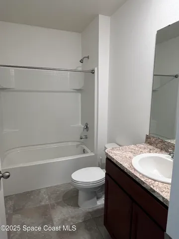 a bathroom with a granite countertop bathtub shower sink vanity and toilet