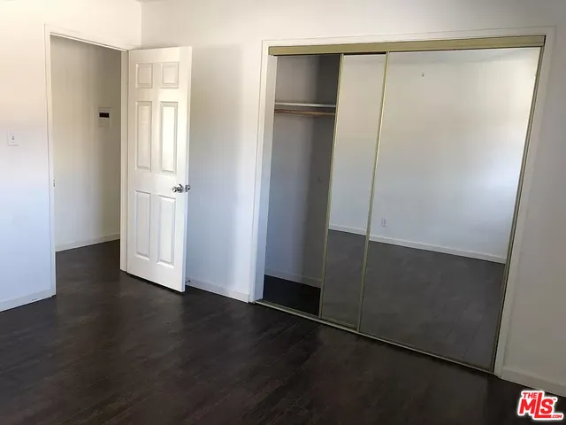 a view of an empty room with wooden floor and closet