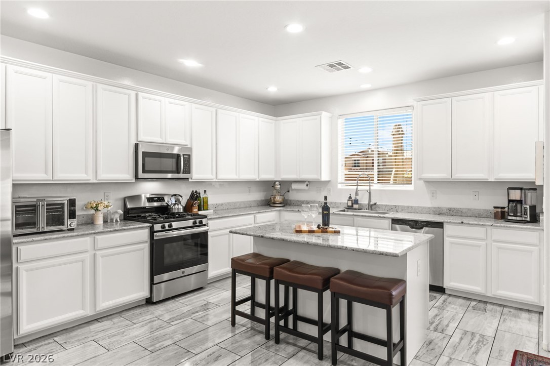 6435 Point Isabel Way Las Vegas, NV 89122 - Photo 2 of 57 A well-appointed kitchen features ample white cabinetry, granite countertops, and stainless steel appliances.