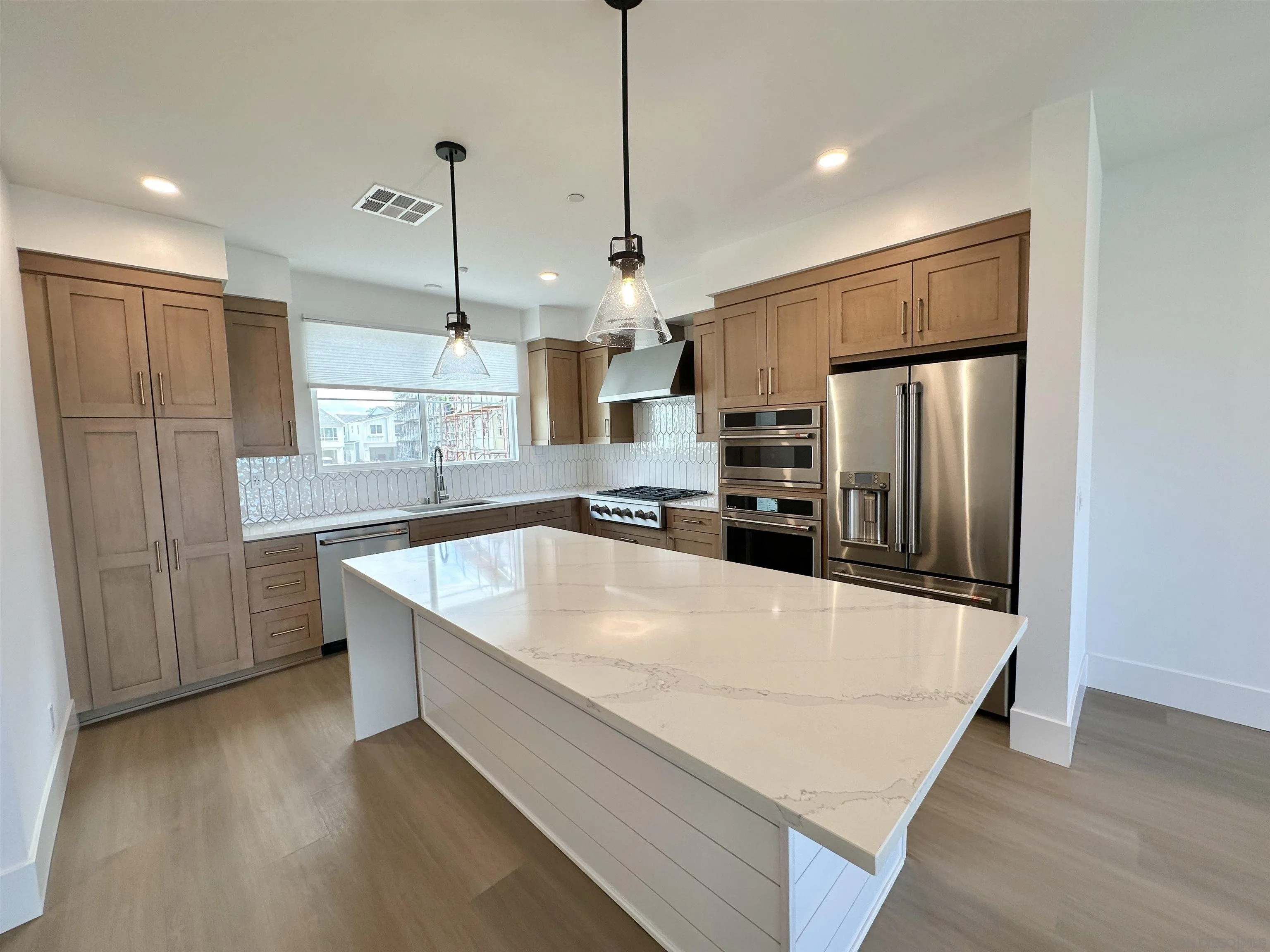 7290 Ponto Drive West, Unit 7132 Carlsbad, CA 92011 - Photo 11 of 44 a large kitchen with stainless steel appliances a large counter top and wooden floor