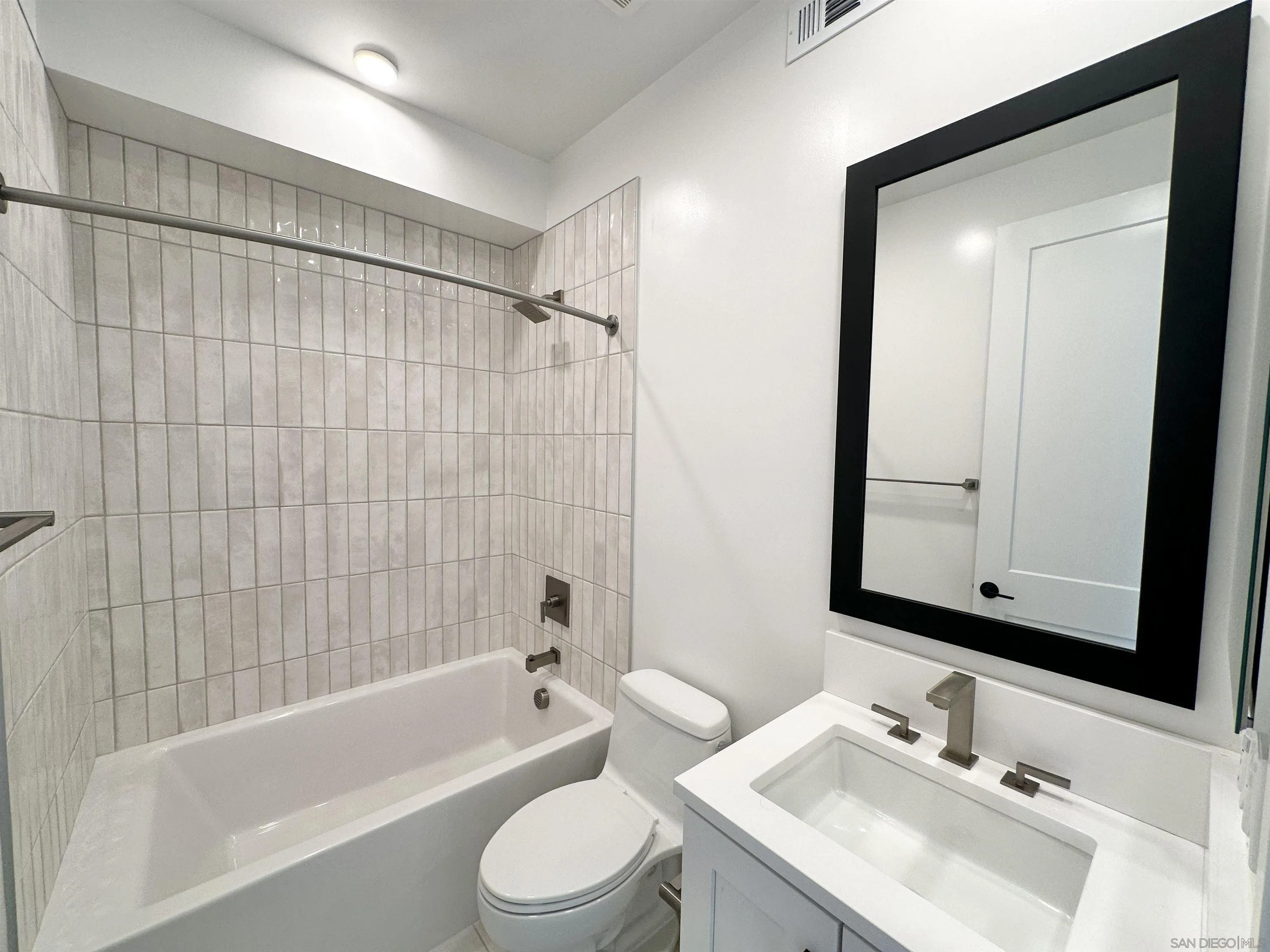 7290 Ponto Drive West, Unit 7132 Carlsbad, CA 92011 - Photo 32 of 44 a bathroom with a bathtub shower sink vanity mirror and toilet