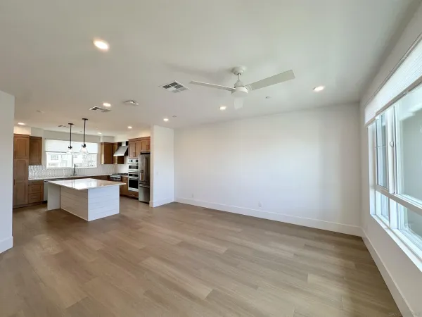 a large kitchen with stainless steel appliances a large counter top and wooden floor