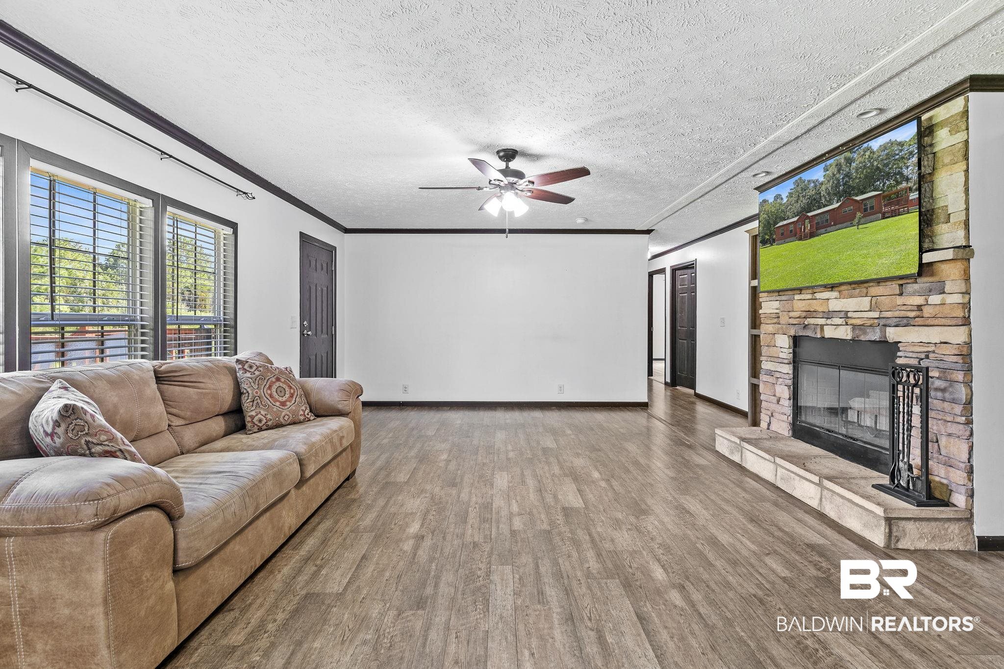 35641 County Road 39 Stapleton, AL 36578 - Photo 12 of 46 Living room featuring a fireplace, a textured ceiling, wood-type flooring, ceiling fan, and ornamental molding
