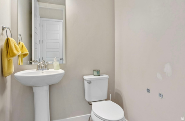 1295 East Granite Peak Road Eagle Mountain, UT 84005 - Photo 28 of 35 Bathroom featuring a white pedestal sink with a chrome faucet, a rectangular wall-mounted mirror, and a white toilet