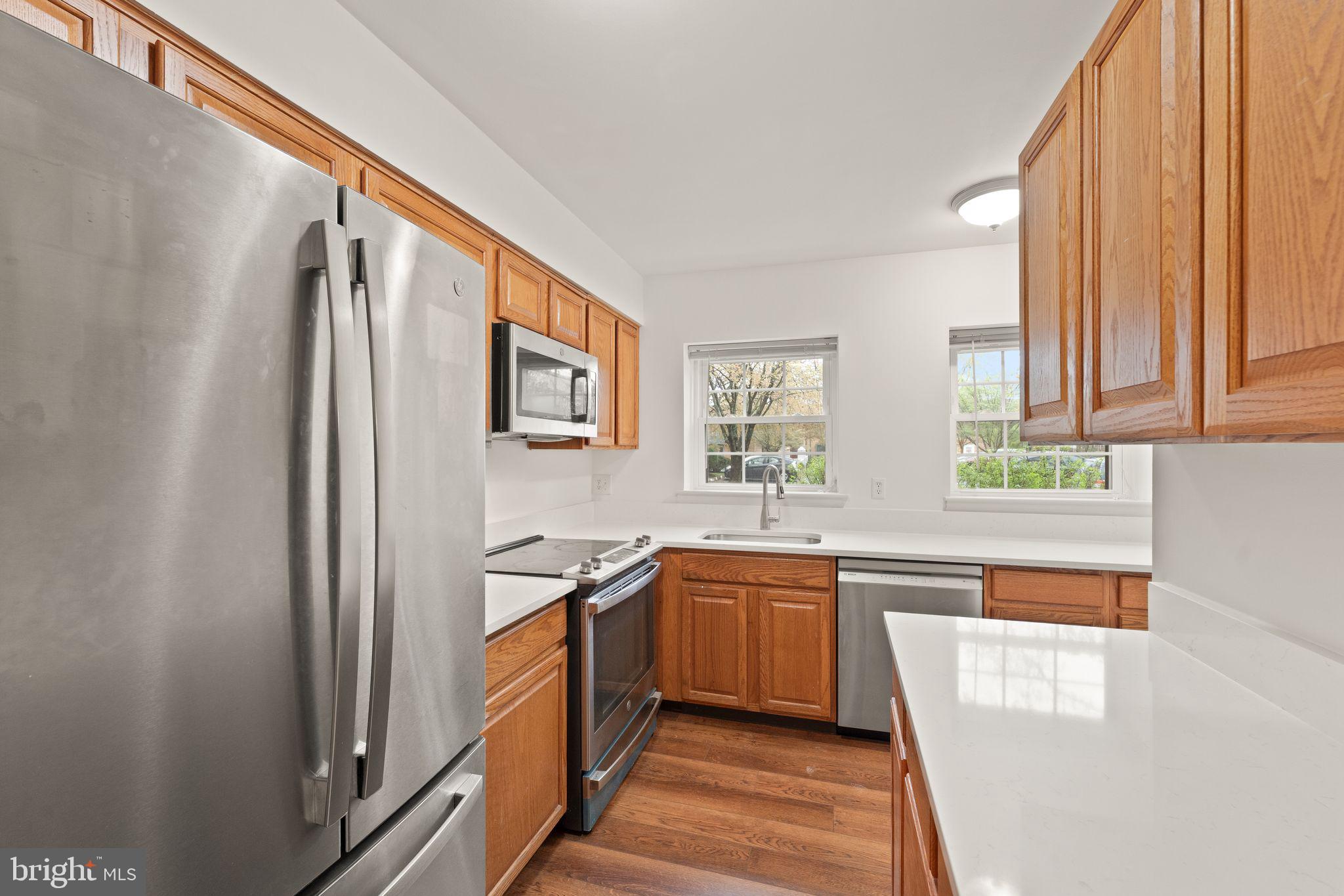 2212 Golf Course Drive Reston, VA 20191 - Photo 9 of 49 a kitchen with stainless steel appliances granite countertop a refrigerator a sink dishwasher a stove and white countertops with wooden floor