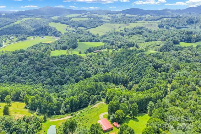 an aerial view of a houses with a lush green hillside