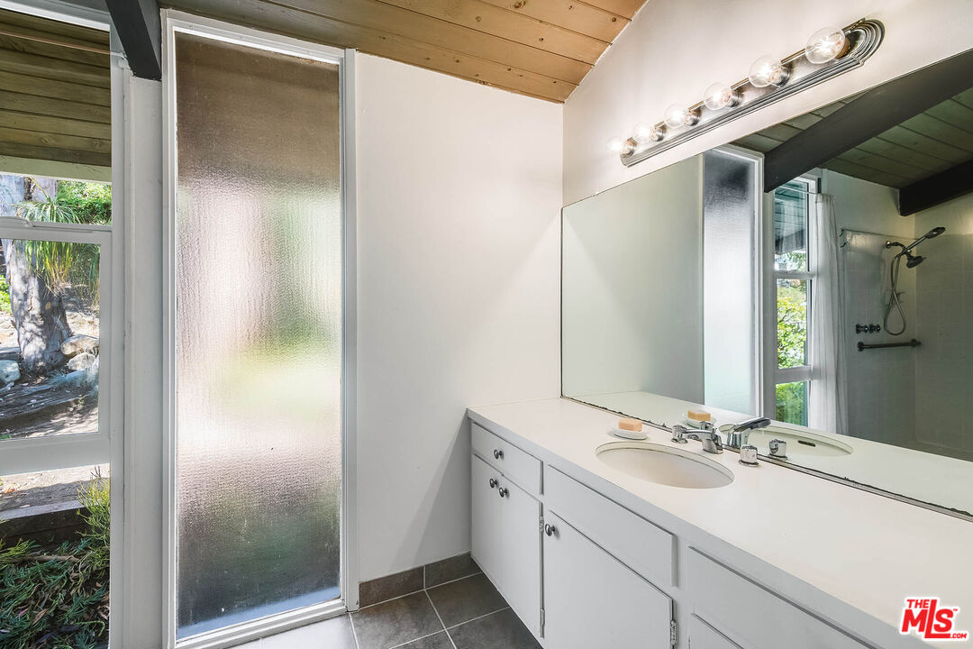 3557 Serra Road Malibu, CA 90265 - Photo 19 of 32 a bathroom with a double vanity sink and mirror