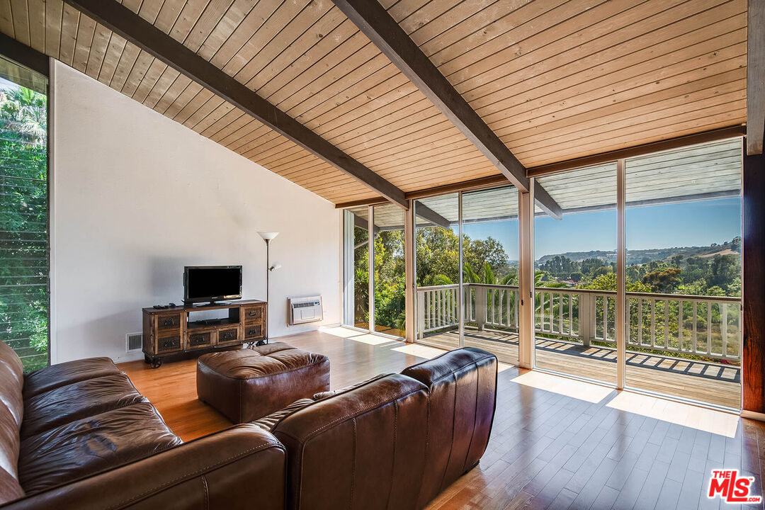 3557 Serra Road Malibu, CA 90265 - Photo 7 of 32 a living room with furniture a flat screen tv and a floor to ceiling window