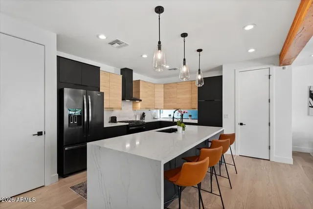a kitchen with stainless steel appliances kitchen island a table chairs in it and wooden floors