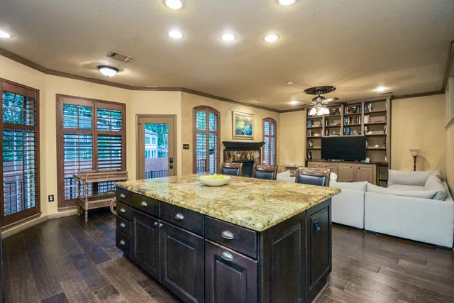 a living room with stainless steel appliances granite countertop a kitchen island a stove and a sink