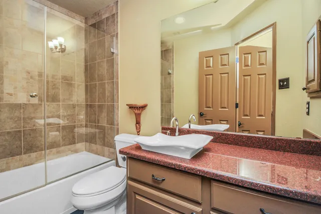 a bathroom with a granite countertop bathtub sink vanity mirror and toilet
