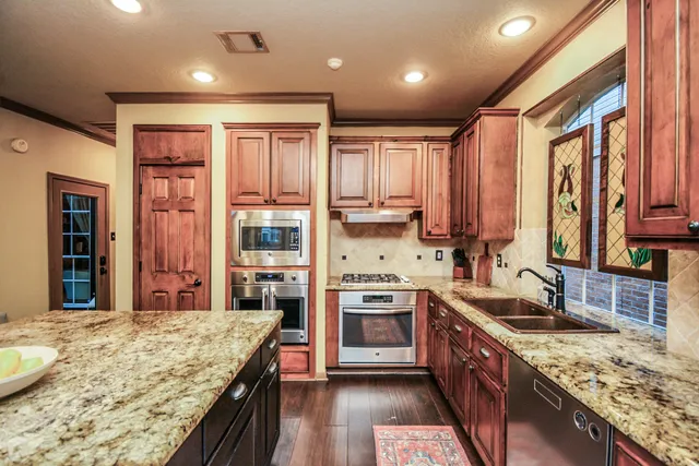a kitchen with stainless steel appliances granite countertop wooden cabinets a stove top oven a sink and dishwasher