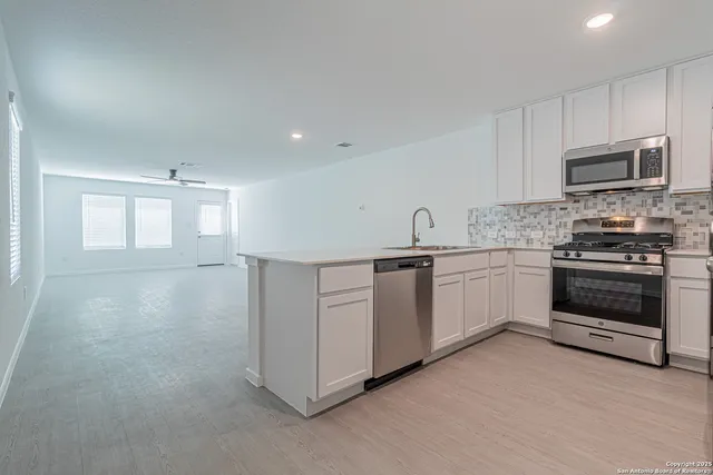 a kitchen with white cabinets and stainless steel appliances