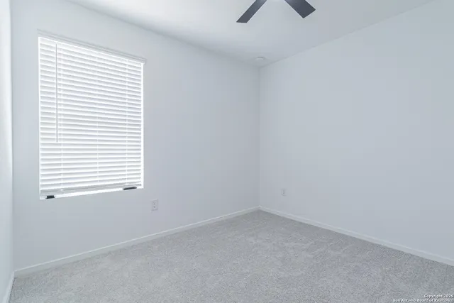 an empty room with a window and a fan