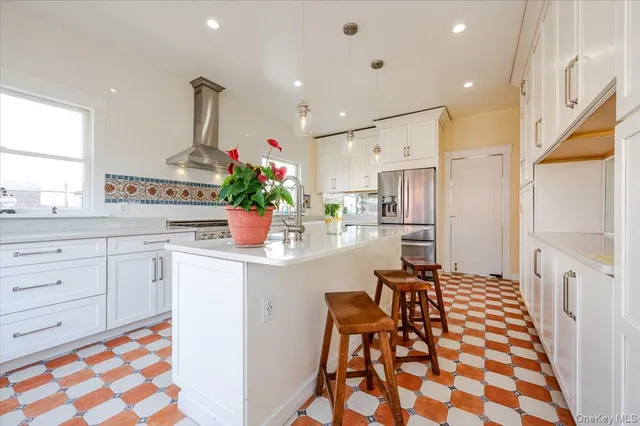 a kitchen with stainless steel appliances kitchen island granite countertop a sink and a refrigerator