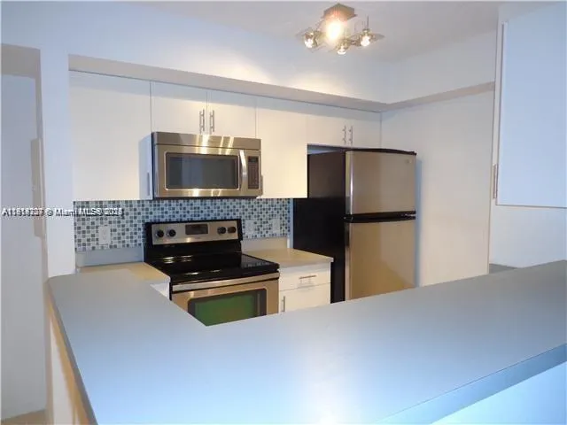 a kitchen with a refrigerator and a stove top oven