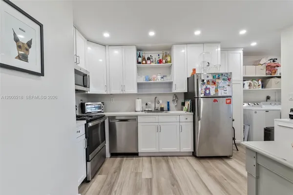 a kitchen with stainless steel appliances granite countertop a refrigerator sink and white cabinets