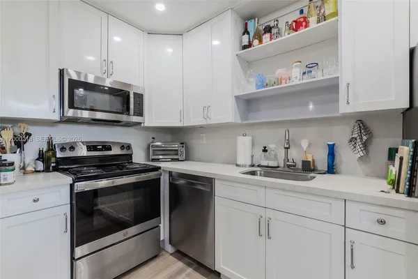 a kitchen with stainless steel appliances granite countertop a sink a stove and cabinets