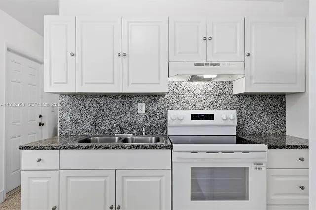 a kitchen with granite countertop white cabinets and a window