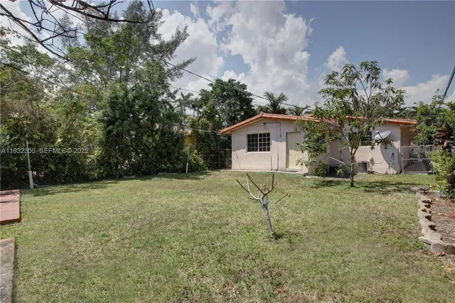 a backyard of a house with plants and large trees