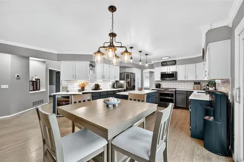 a dining room with stainless steel appliances kitchen island granite countertop a table chairs and a refrigerator