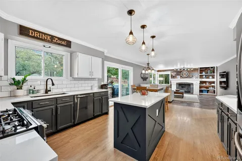 a kitchen with a stove a counter space a sink dishwasher and a fireplace with wooden floor
